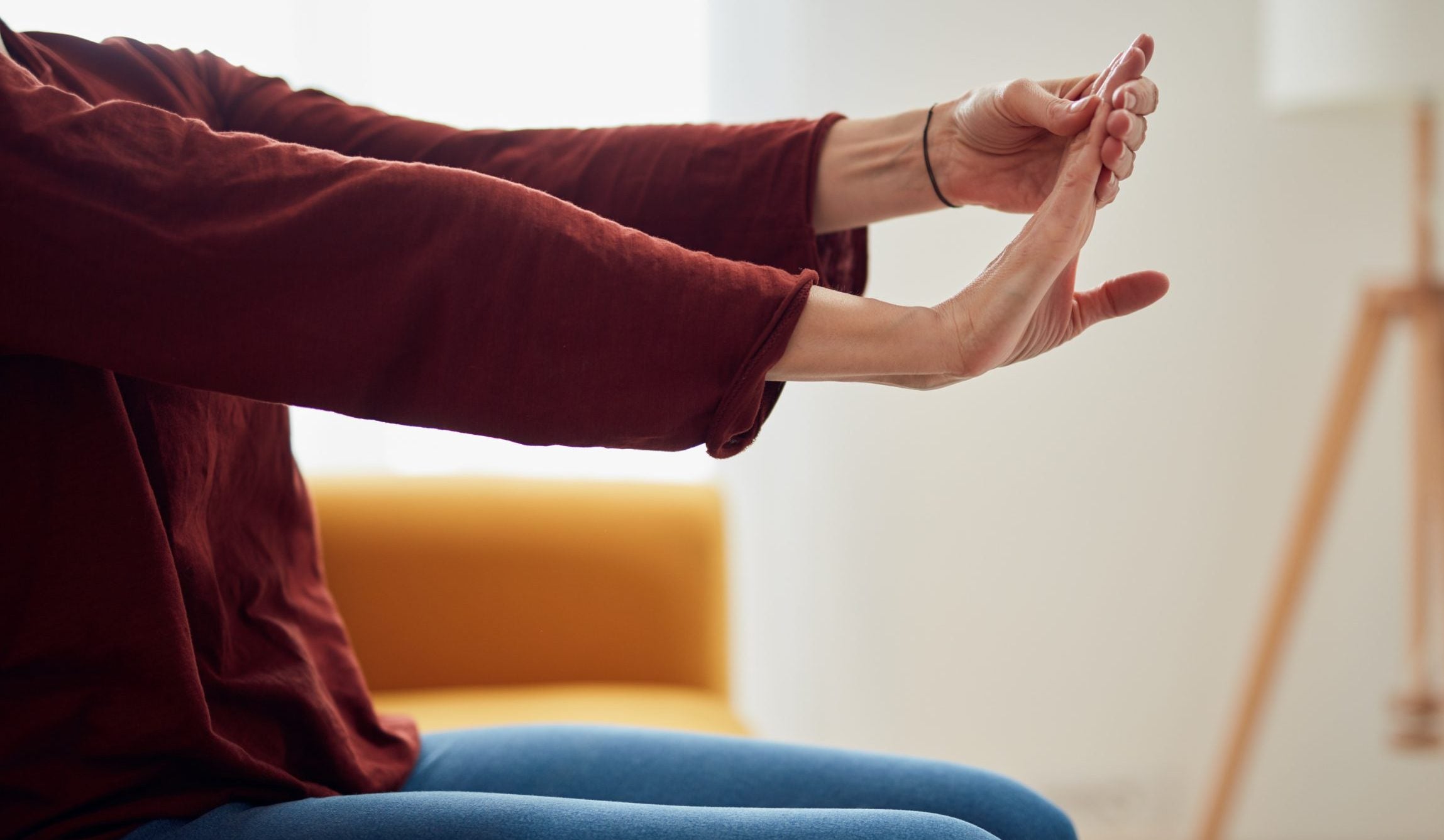 Woman with hand pain sitting on a couch at home.